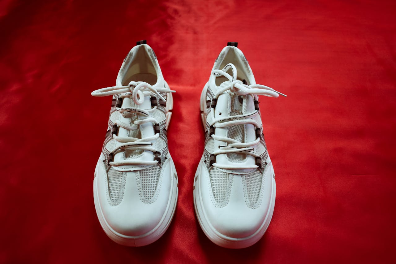 services-05 Top view of fashionable white sneakers on a bold red background, perfect for footwear fashion and design.